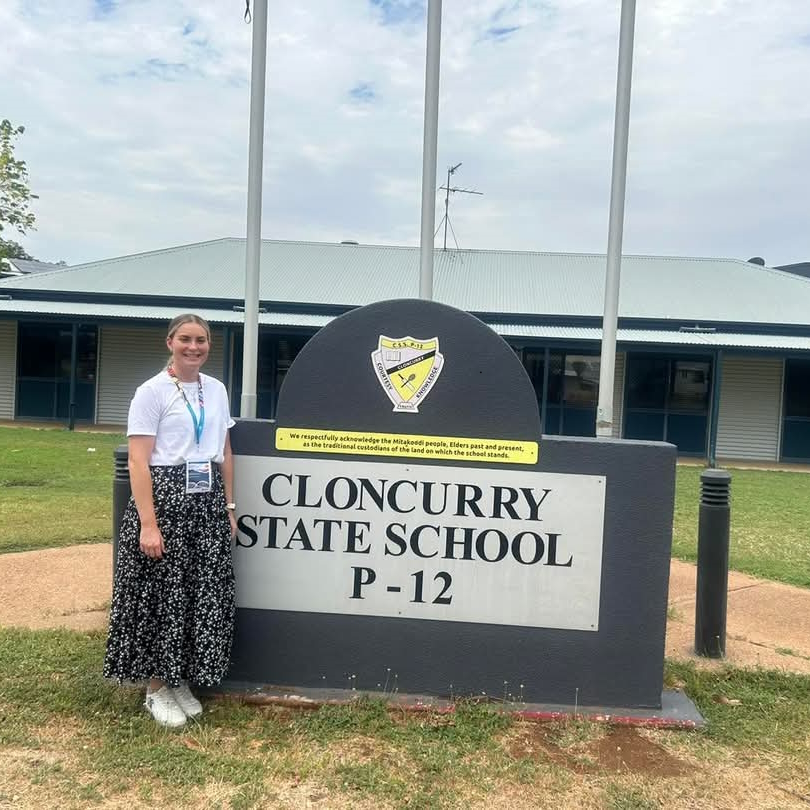 Angela stands in front of sign that says ‘Cloncurry State School P-12
