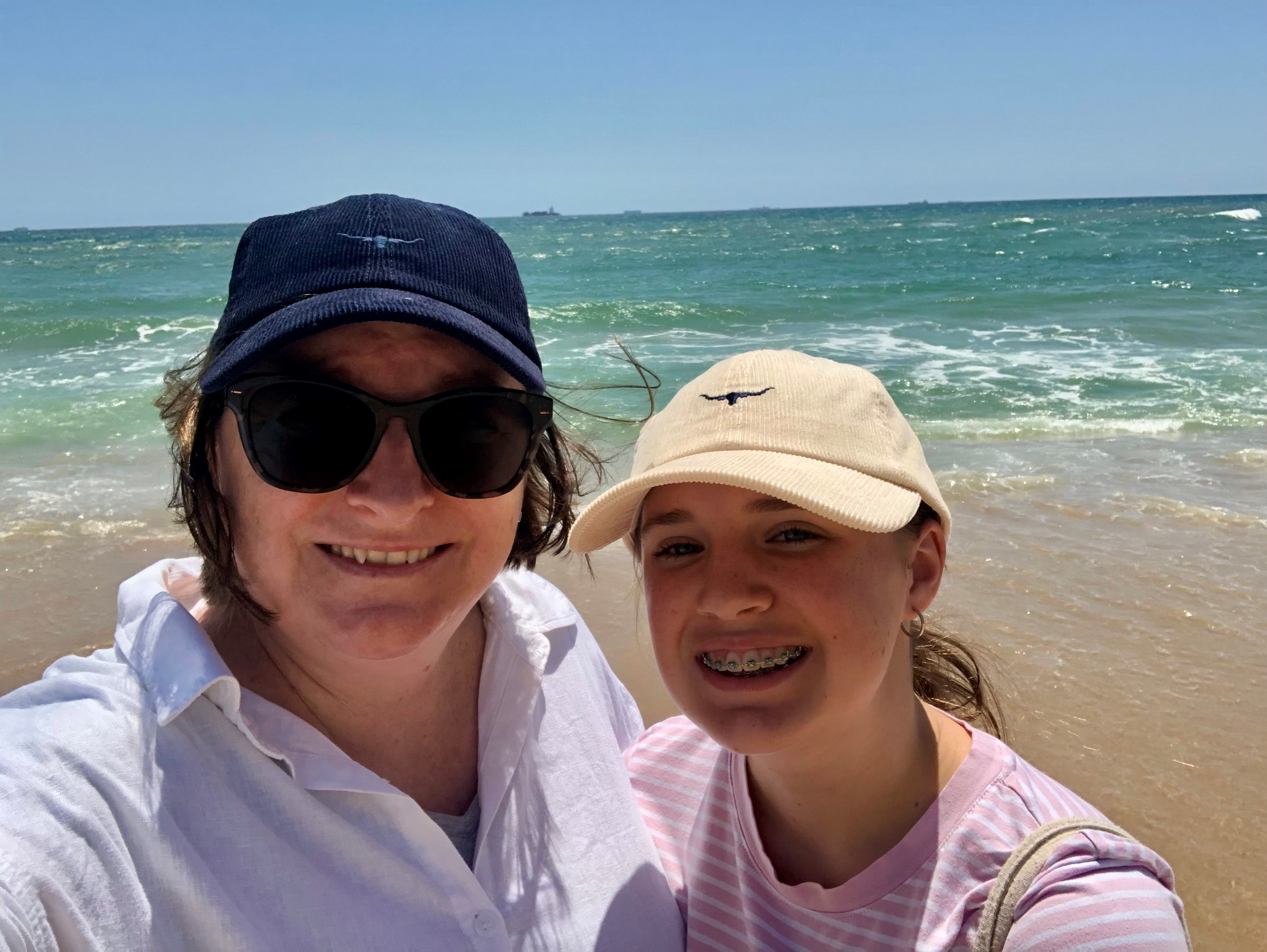 Photo of Belinda and child at the beach, smiling at the camera.