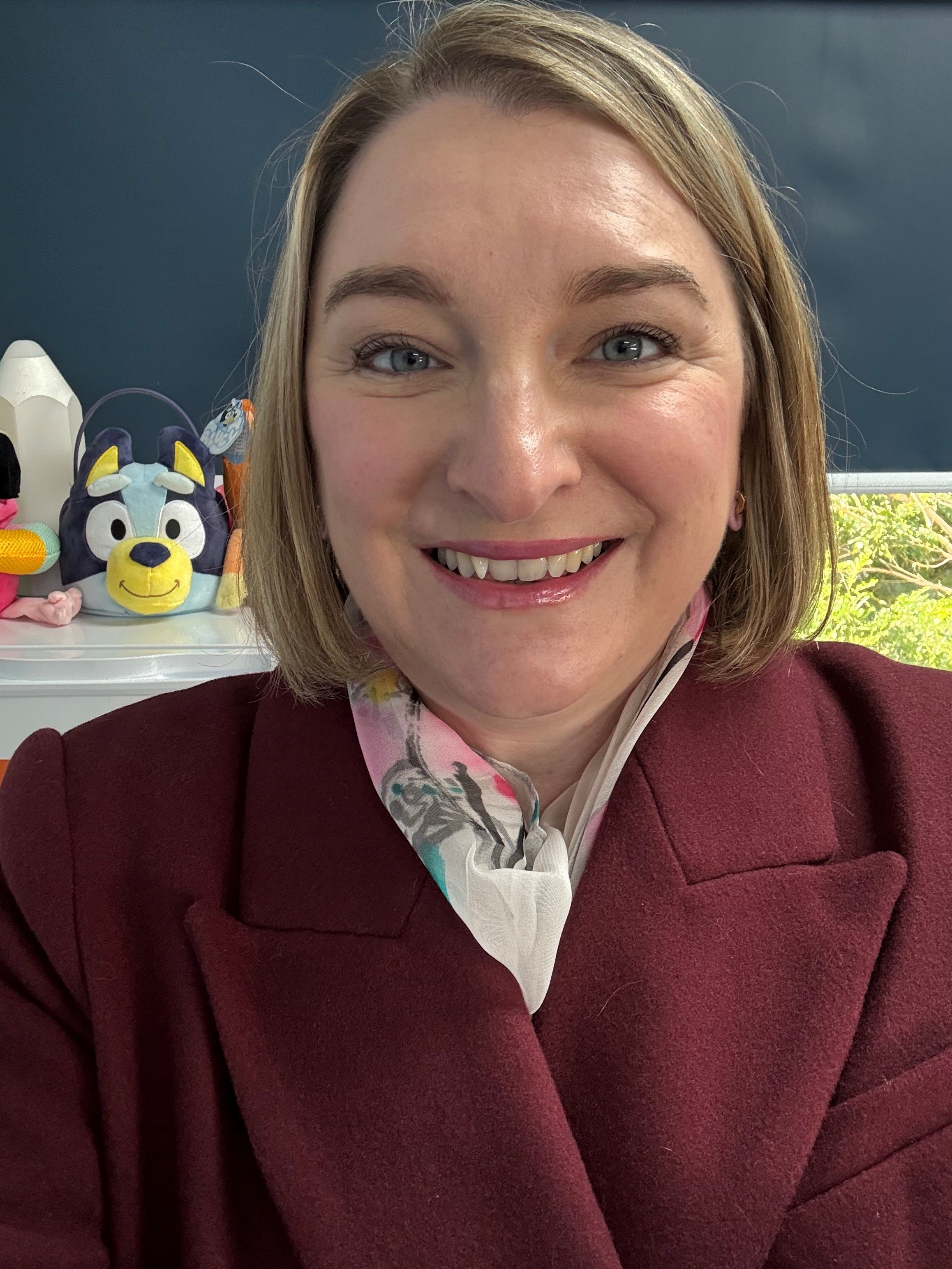 Photo of teacher, Belinda, with a blonde bob and maroon jacket, smiling at the camera.