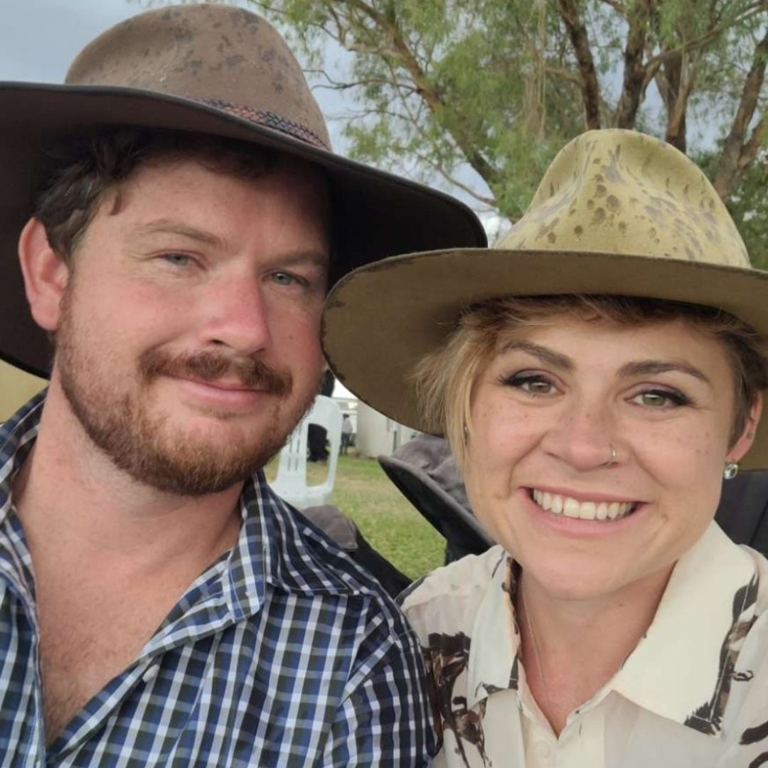 Photo of male and female teacher smiling at the camera and with akubra hats on.