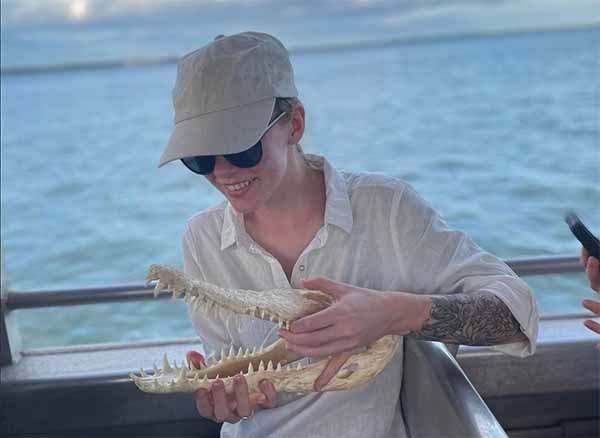 Teacher on a boat holding a crocodile skull.