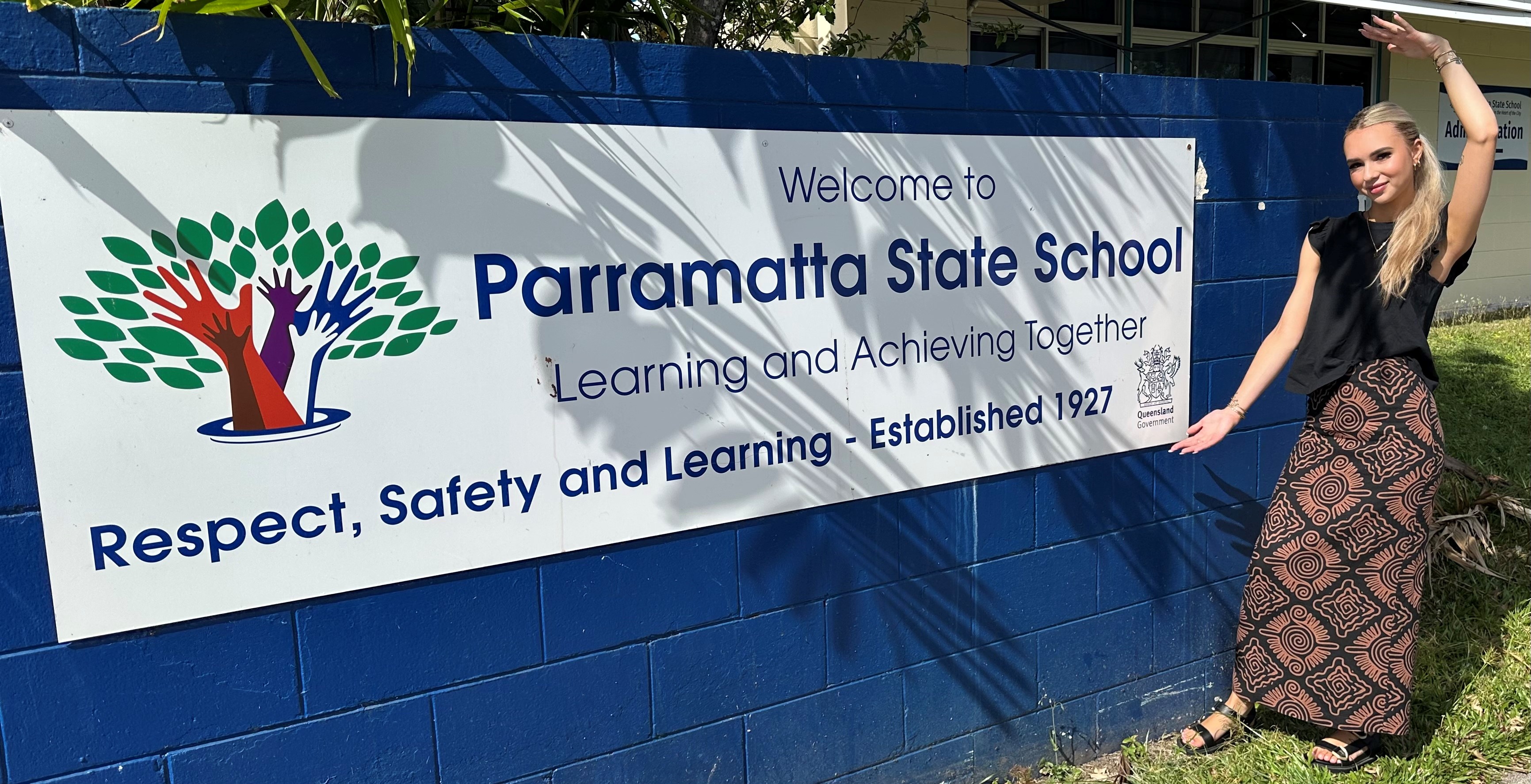 Holly standing in front of the Paramatta State School sign.